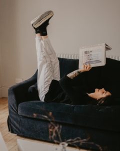 man in white pants lying on black couch