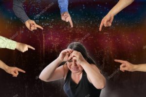 woman crying, closing her hands protective hand gestures, many hands show accusatory gestures, concept of psychological mobbing, gaslighting