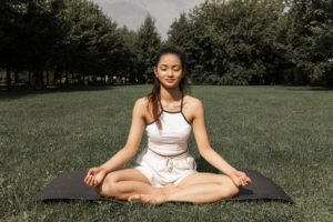 Charming woman doing lotus pose in nature