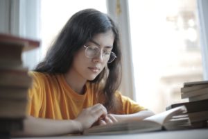 Clever female student reading book in library