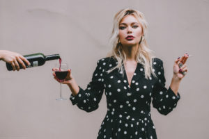 Confident woman standing with wineglass and cigarette