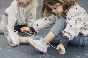 Crop girl tying shoelaces on playground