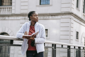 Dreamy black student with agenda against urban building