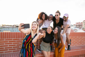 Excited young diverse men and women taking selfie on rooftop