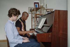 Man and teenage boy sitting by the piano