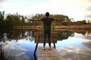 Man standing on boardwalk on front of body of water