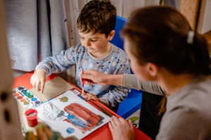 Mother painting picture with watercolor paints with son