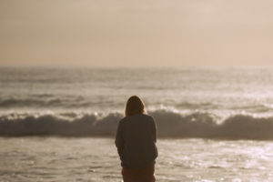 Person standing on shore and admiring wavy ocean in sunlight