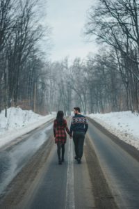 Photo of couple walking on road near bare trees