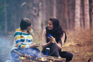 Two women sitting on ground near bonfire