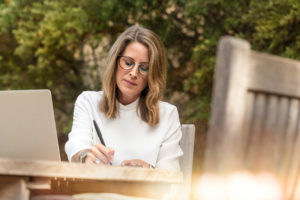 Woman sitting on gray chair while writing on table