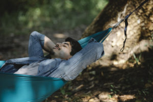 Dreamy man resting in hammock in woods